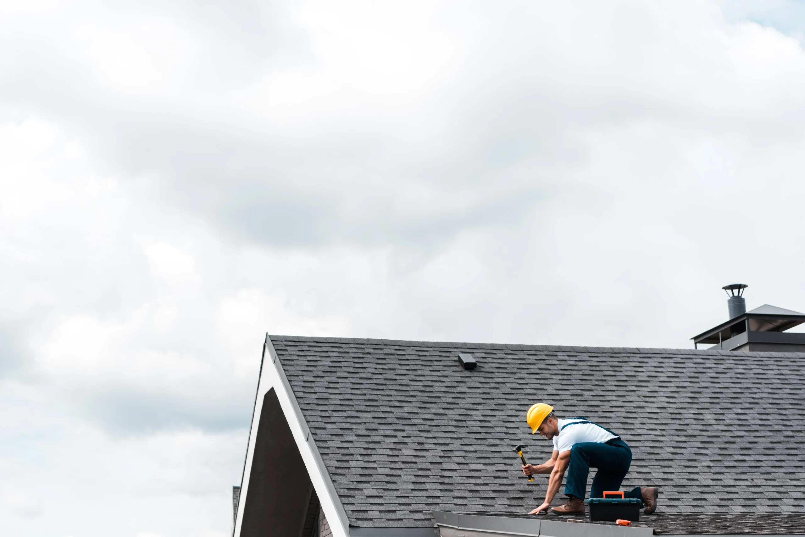 Professional roofer on a residential roof with tools, ensuring safe and expert roof repair.