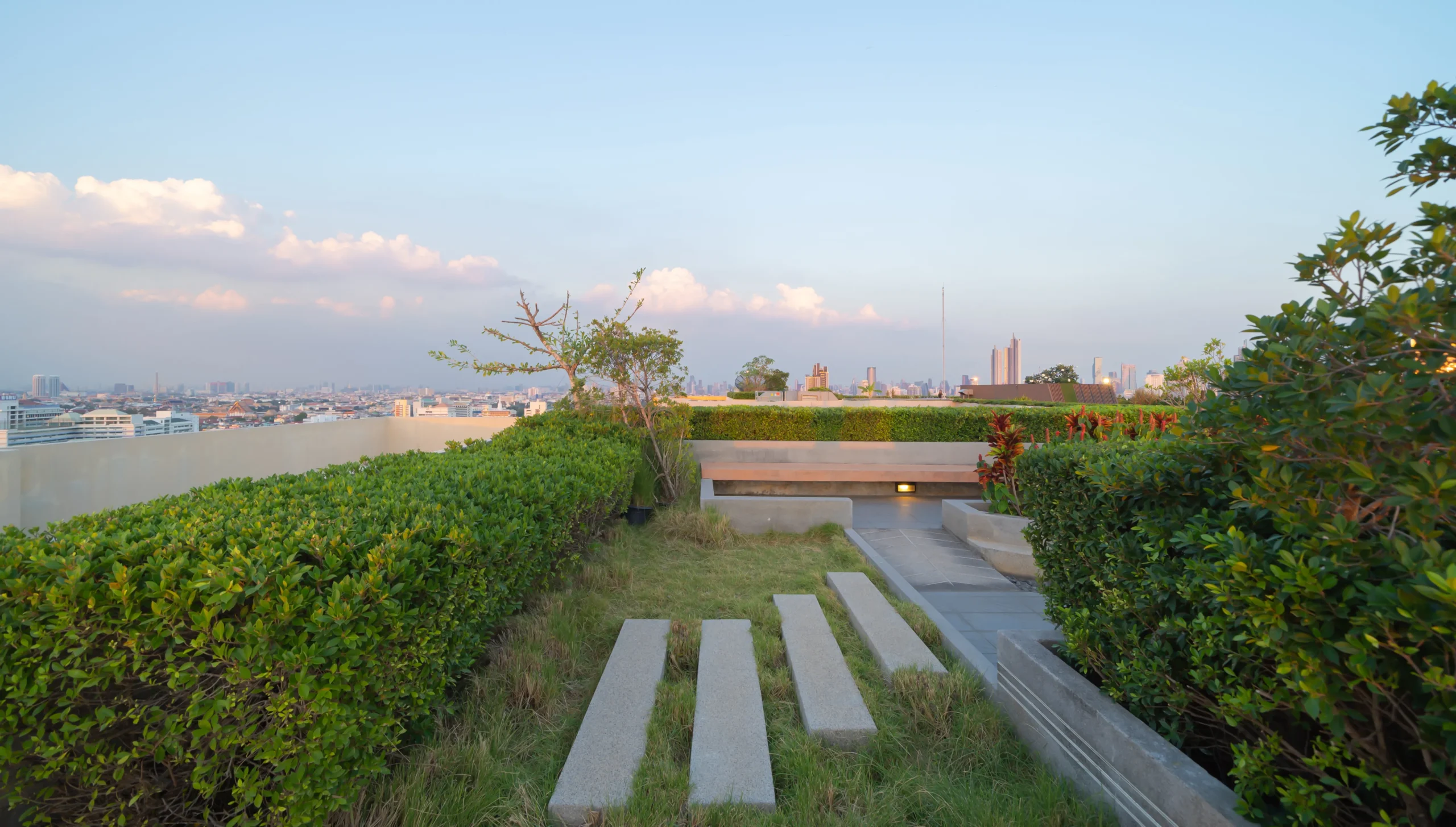 Green commercial roofing system with landscaped garden and city skyline view